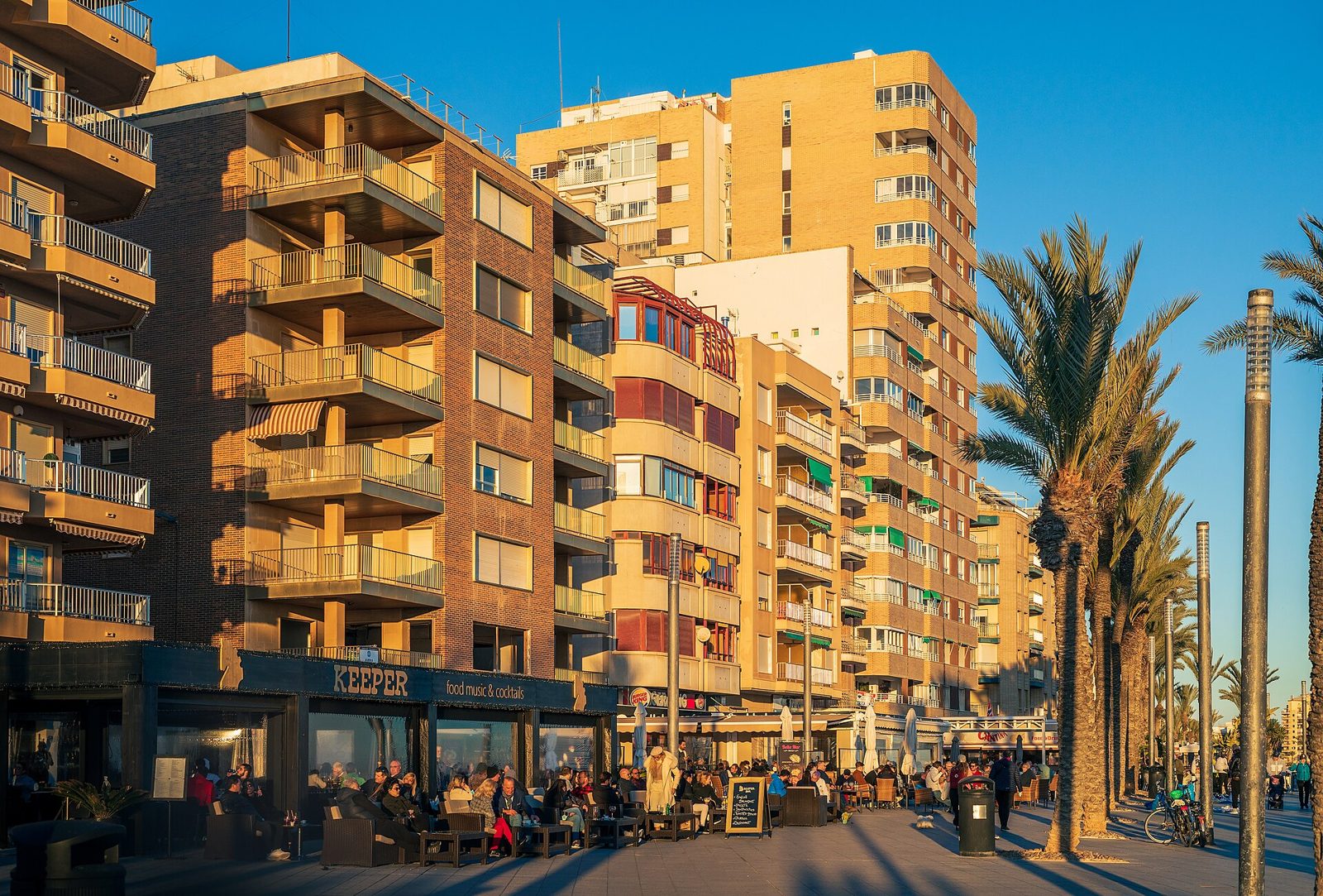Strandpromenaden Paseo Juan Aparicio i Torrevieja en solig vinterdag i januari med uteserveringar och palmer